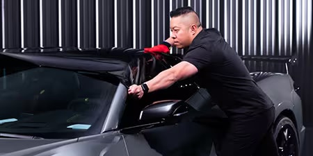 Installateur de covering appliquant un film sur le toit d'un véhicule.
