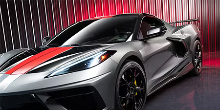 Photo d'un coupé gris avec un covering de capot rouge.

