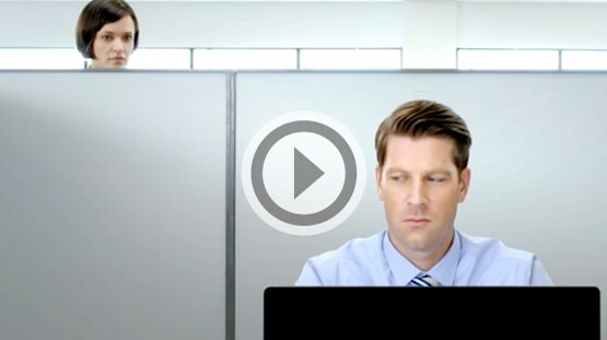 Femme regardant par-dessus une étagère l'ordinateur portable d'un collègue